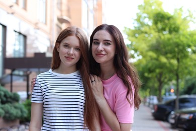 Photo of Portrait of beautiful mother and her teenage daughter on city street
