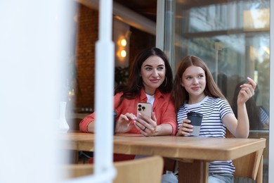 Photo of Mother and her teenage daughter spending time together at table in cafe