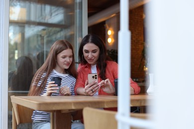 Photo of Mother and her teenage daughter spending time together at table in cafe