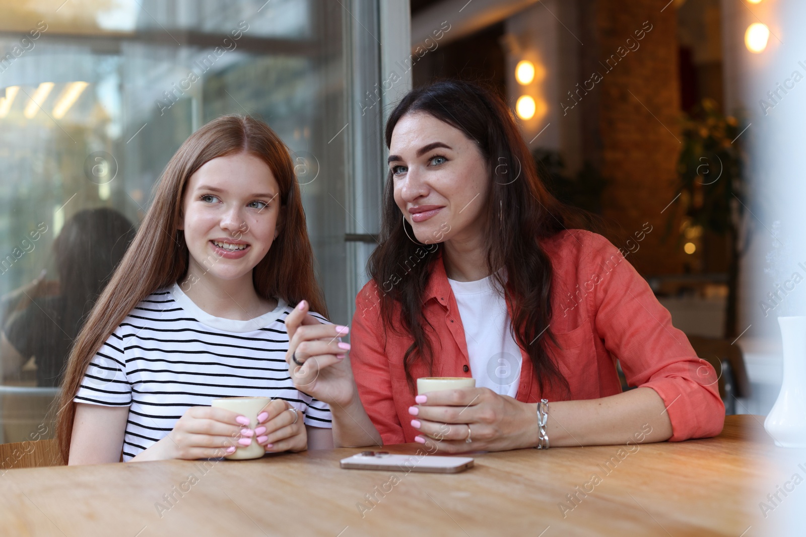 Mother and her teenage daughter drinking coffee at table in cafe Photo of Mother and her teenage daughter drinking coffee at table in cafe