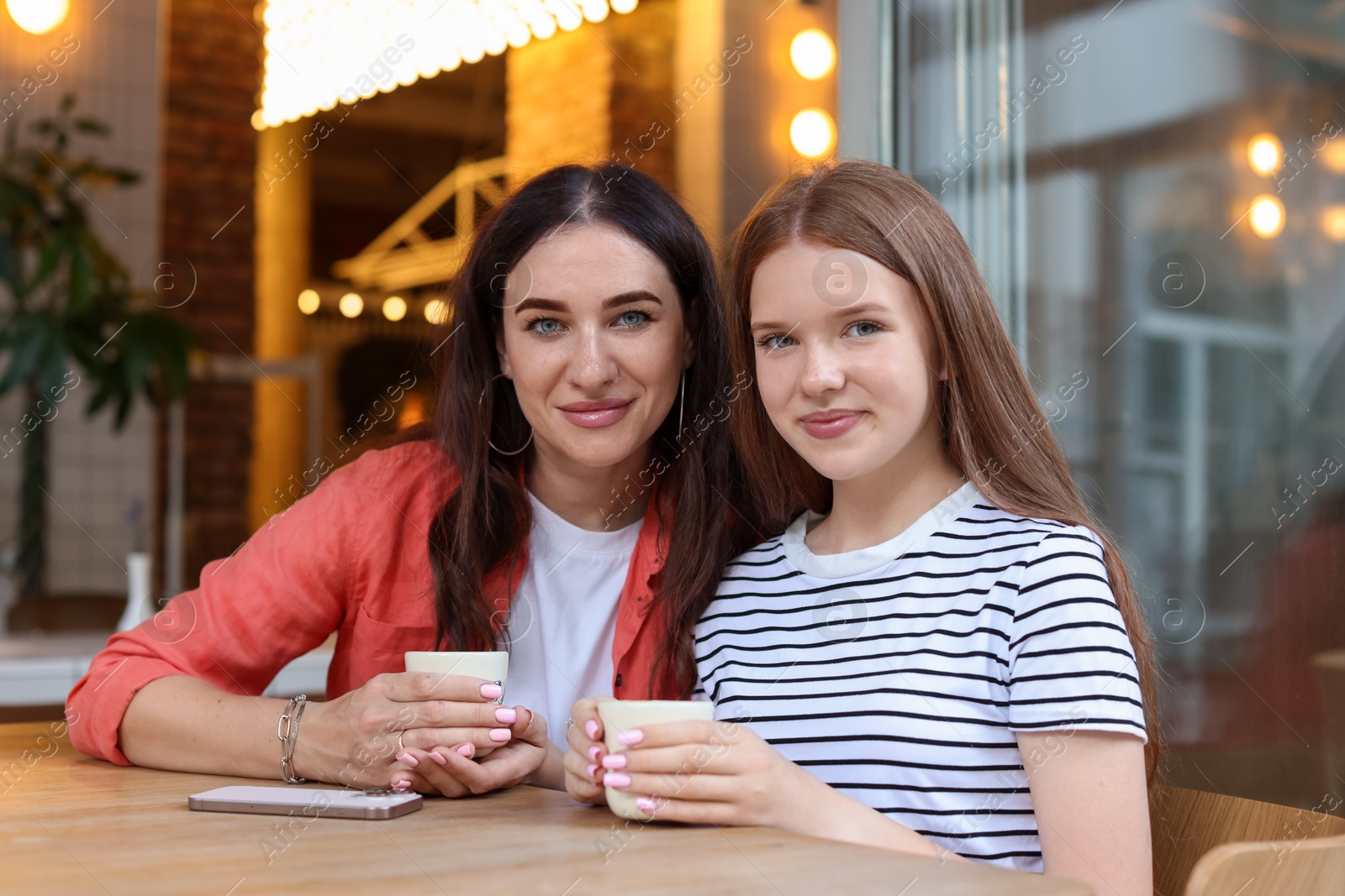 Mother and her teenage daughter drinking coffee at table in cafe Photo of Mother and her teenage daughter drinking coffee at table in cafe