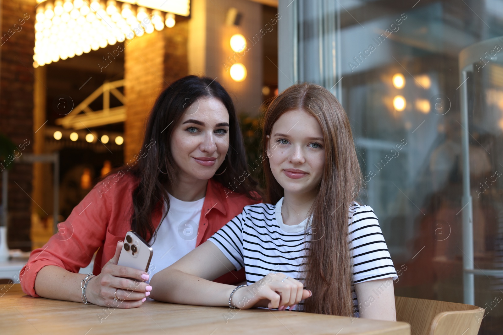 Mother and her teenage daughter with smartphone at table in cafe Photo of Mother and her teenage daughter with smartphone at table in cafe