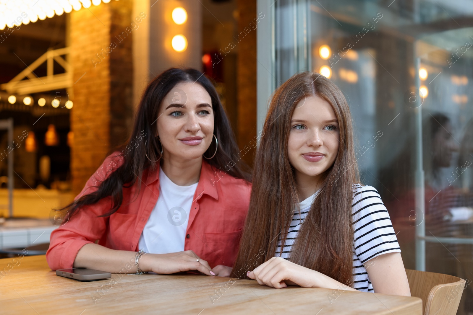 Mother and her teenage daughter spending time together at table in cafe Photo of Mother and her teenage daughter spending time together at table in cafe