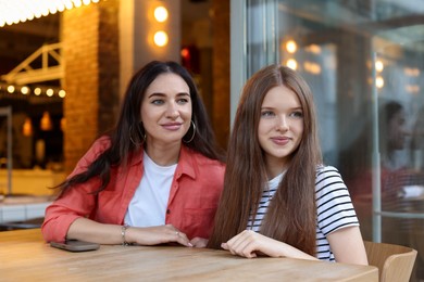 Photo of Mother and her teenage daughter spending time together at table in cafe