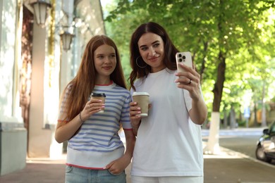 Photo of Mother and her teenage daughter taking selfie outdoors