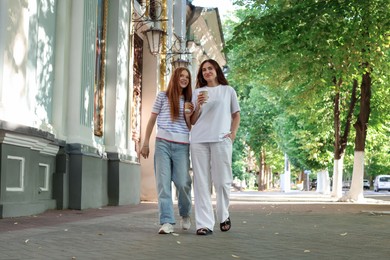 Photo of Mother and her teenage daughter walking outdoors, low angle view