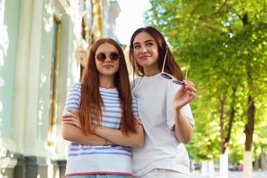 Photo of Portrait of beautiful mother and her teenage daughter in sunglasses on city street