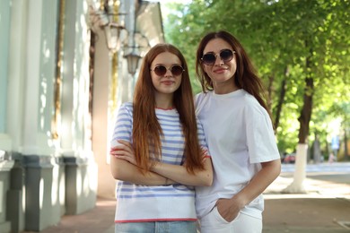 Photo of Portrait of beautiful mother and her teenage daughter in sunglasses on city street