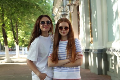 Photo of Portrait of beautiful mother and her teenage daughter in sunglasses on city street