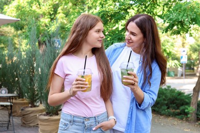 Photo of Beautiful mother and her teenage daughter with refreshing drinks outdoors