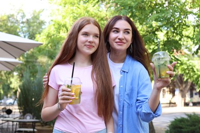 Photo of Beautiful mother and her teenage daughter with refreshing drinks outdoors