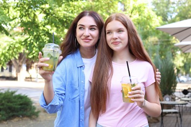 Photo of Beautiful mother and her teenage daughter with refreshing drinks outdoors