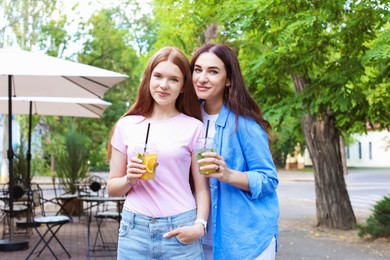 Photo of Portrait of beautiful mother and her teenage daughter with refreshing drinks outdoors