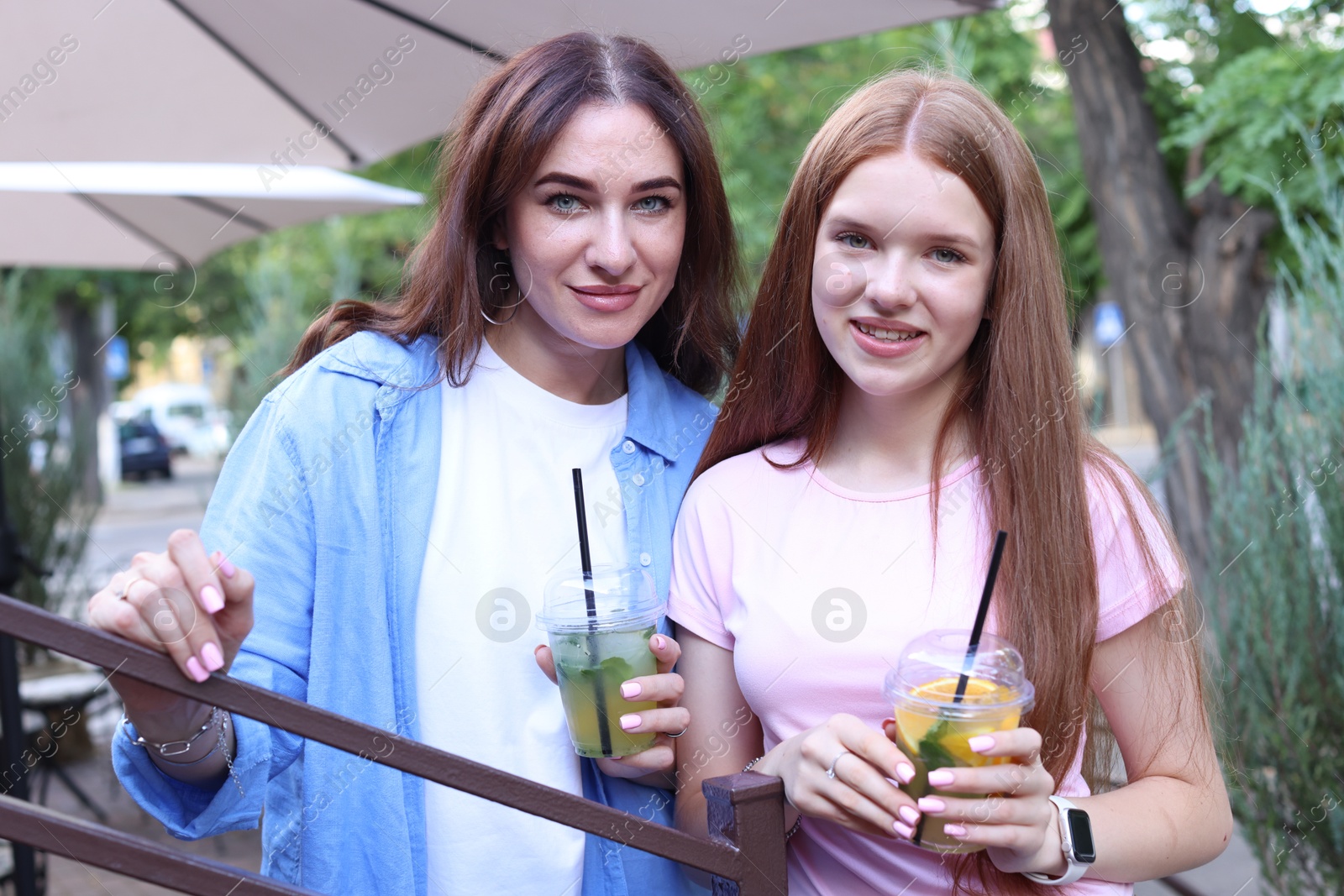 Portrait of beautiful mother and her teenage daughter with refreshing drinks outdoors Photo of Portrait of beautiful mother and her teenage daughter with refreshing drinks outdoors