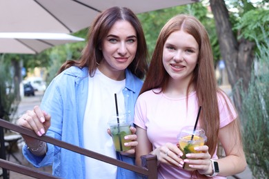 Photo of Portrait of beautiful mother and her teenage daughter with refreshing drinks outdoors