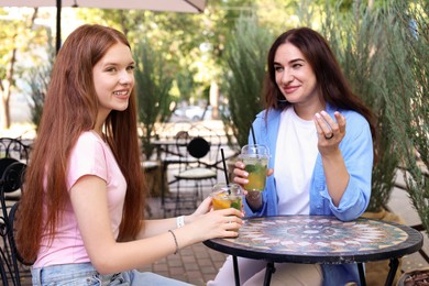 Photo of Beautiful mother and her teenage daughter spending time together in outdoor cafe