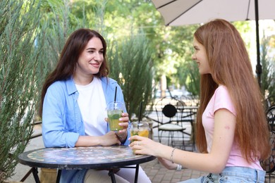 Photo of Beautiful mother and her teenage daughter spending time together in outdoor cafe