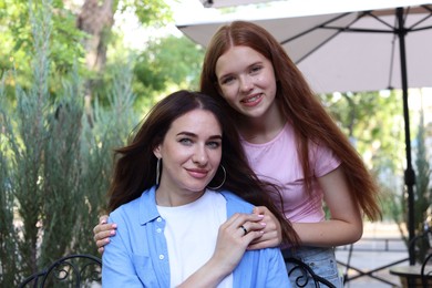 Photo of Portrait of beautiful mother and her teenage daughter in outdoor cafe