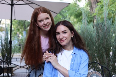 Photo of Portrait of beautiful mother and her teenage daughter in outdoor cafe