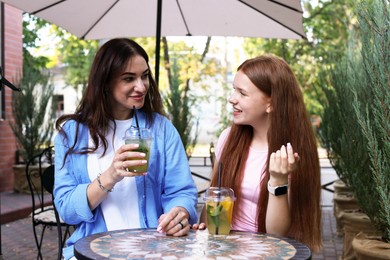Photo of Beautiful mother and her teenage daughter spending time together in outdoor cafe