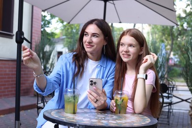 Photo of Beautiful mother and her teenage daughter spending time together in outdoor cafe