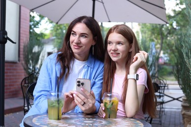 Photo of Beautiful mother and her teenage daughter spending time together in outdoor cafe