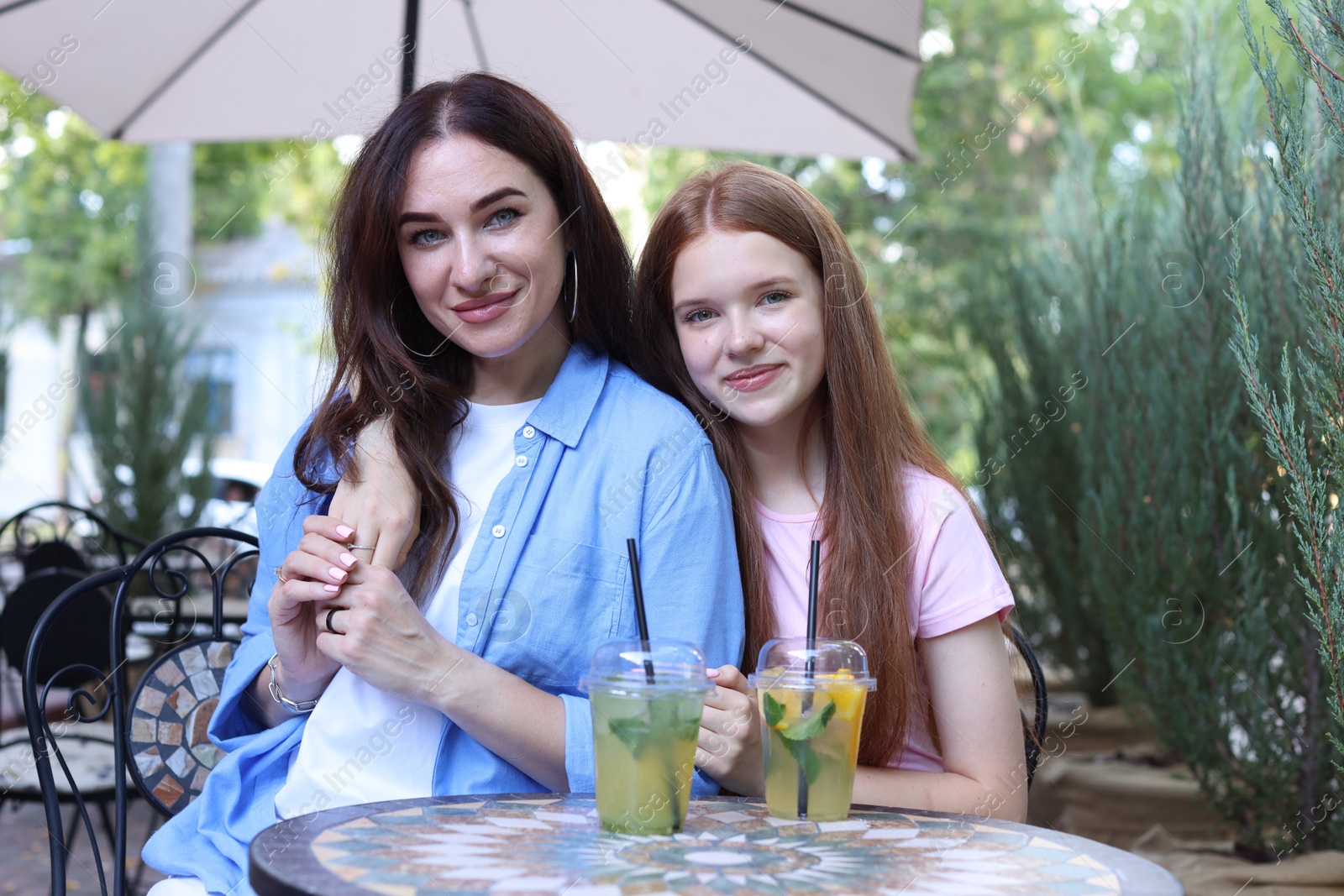 Photo of Portrait of beautiful mother and her teenage daughter in outdoor cafe