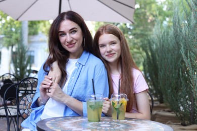 Photo of Portrait of beautiful mother and her teenage daughter in outdoor cafe
