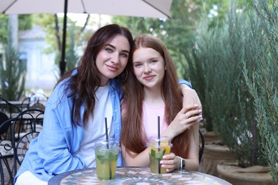 Photo of Portrait of beautiful mother and her teenage daughter in outdoor cafe