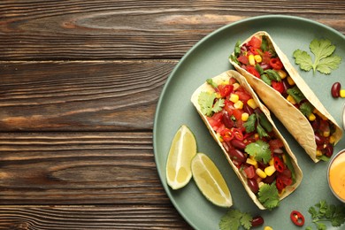 Photo of Tasty vegetarian tacos served on wooden table, top view. Space for text