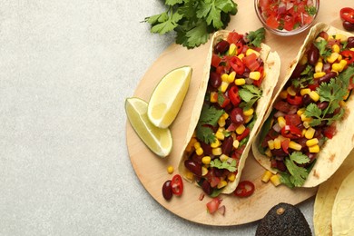 Photo of Tasty vegetarian tacos and ingredients on light grey table, flat lay. Space for text