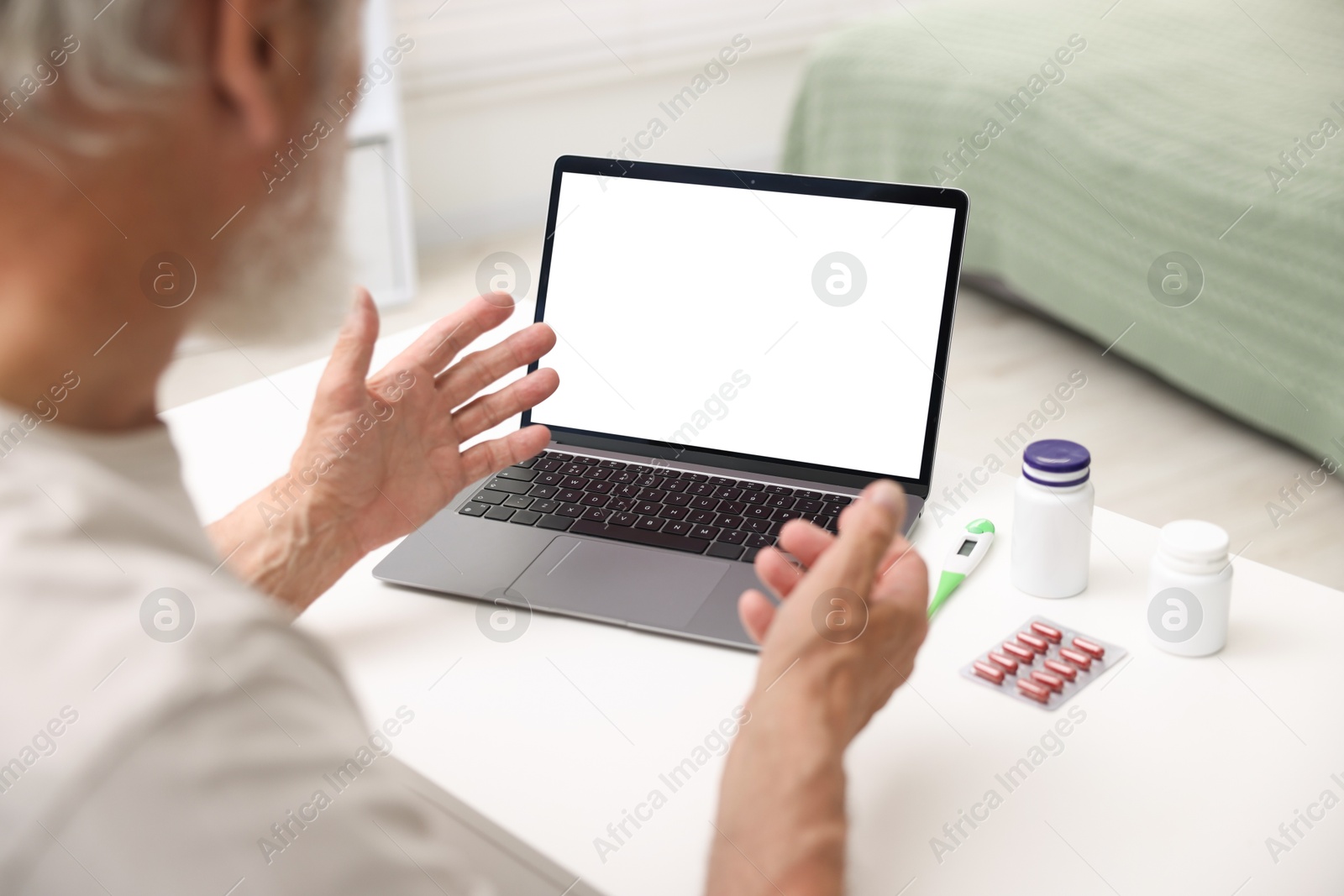 Senior man having online consultation with doctor via laptop at table indoors, closeup Photo of Senior man having online consultation with doctor via laptop at table indoors, closeup
