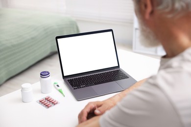 Photo of Senior man having online consultation with doctor via laptop at table indoors, closeup