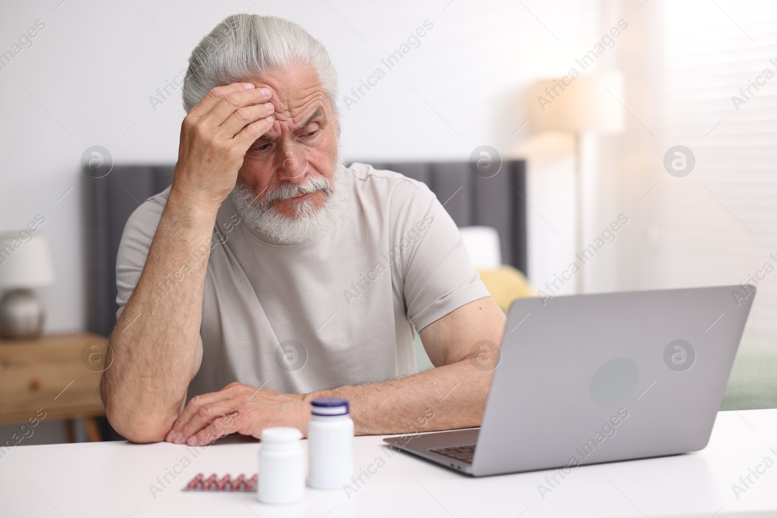 Senior man having online consultation with doctor via laptop at table indoors Photo of Senior man having online consultation with doctor via laptop at table indoors