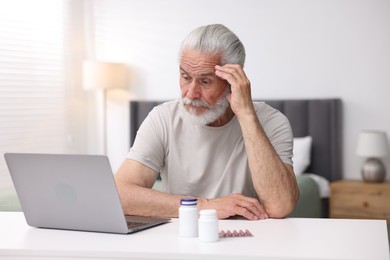 Photo of Senior man having online consultation with doctor via laptop at table indoors