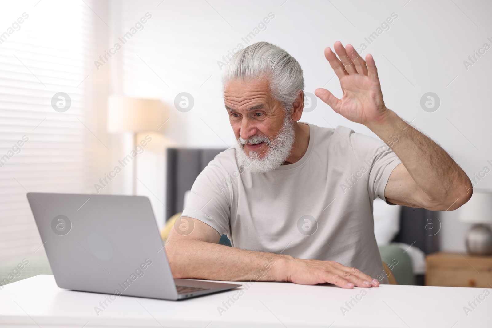 Senior man having online consultation with doctor via laptop at table indoors Photo of Senior man having online consultation with doctor via laptop at table indoors