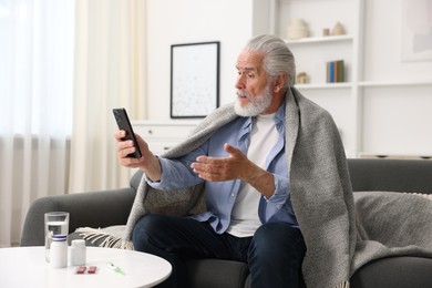 Photo of Senior man having online consultation with doctor via smartphone at home