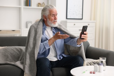 Photo of Senior man having online consultation with doctor via smartphone at home