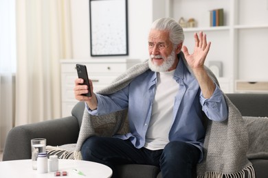 Photo of Senior man having online consultation with doctor via smartphone at home