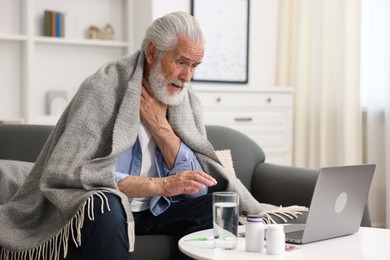Photo of Senior man having online consultation with doctor via laptop at home