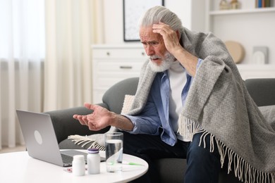 Photo of Senior man having online consultation with doctor via laptop at home