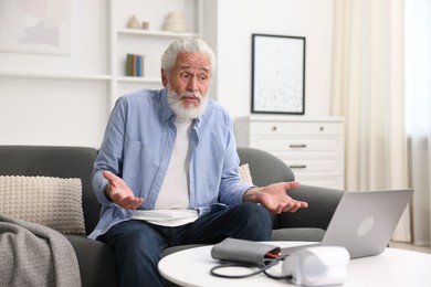 Photo of Senior man having online consultation with doctor via laptop at home
