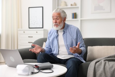 Photo of Senior man having online consultation with doctor via laptop at home
