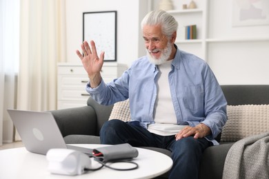 Photo of Senior man having online consultation with doctor via laptop at home