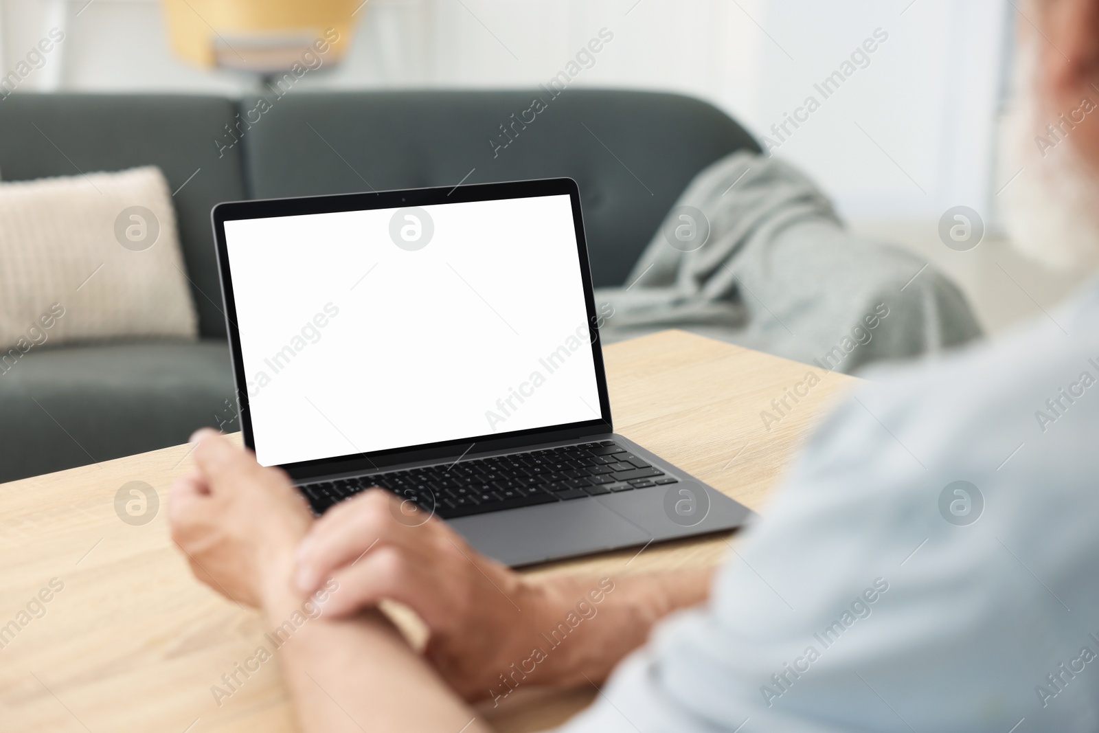 Photo of Senior man having online consultation with doctor via laptop at table indoors, closeup