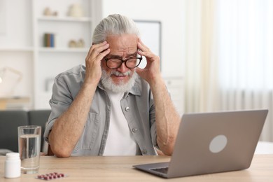 Photo of Senior man having online consultation with doctor via laptop at table indoors