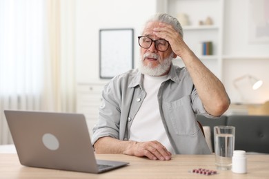 Photo of Senior man having online consultation with doctor via laptop at table indoors