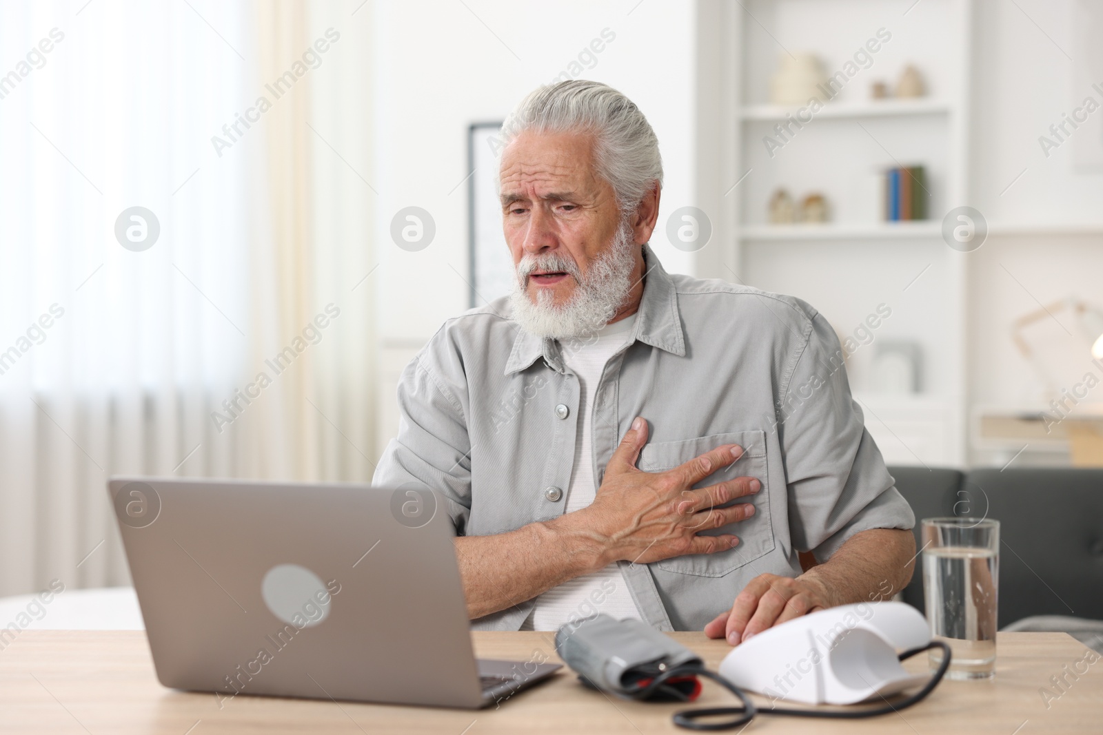 Senior man having online consultation with doctor via laptop at table indoors Photo of Senior man having online consultation with doctor via laptop at table indoors