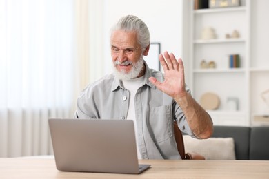 Photo of Senior man having online consultation with doctor via laptop at table indoors