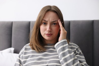 Photo of Woman suffering from headache at home. Online medical consultation